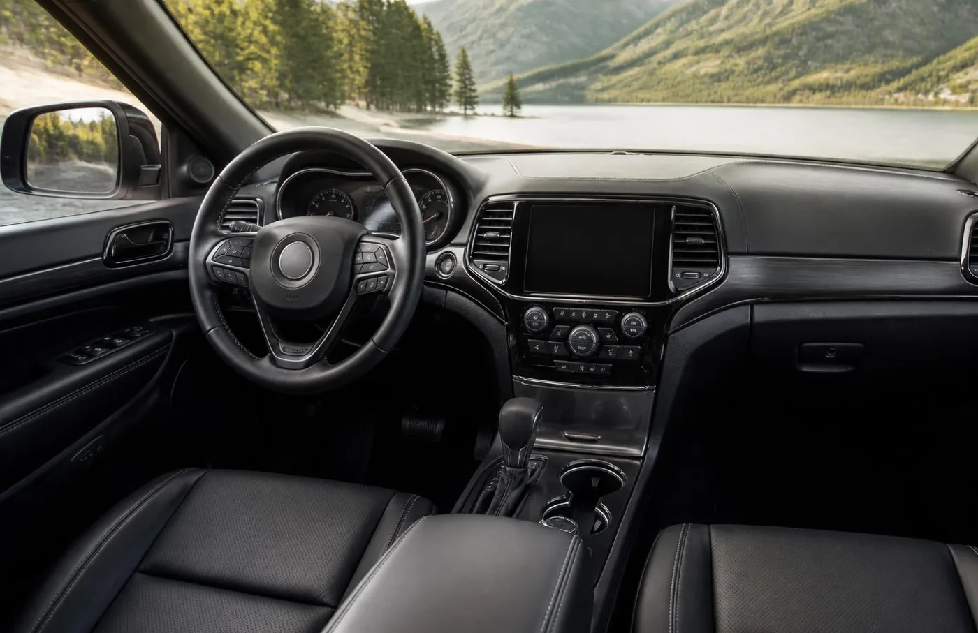 Interior of a Jeep SUV showing the steering wheel, dashboard and infotainment touchscreen