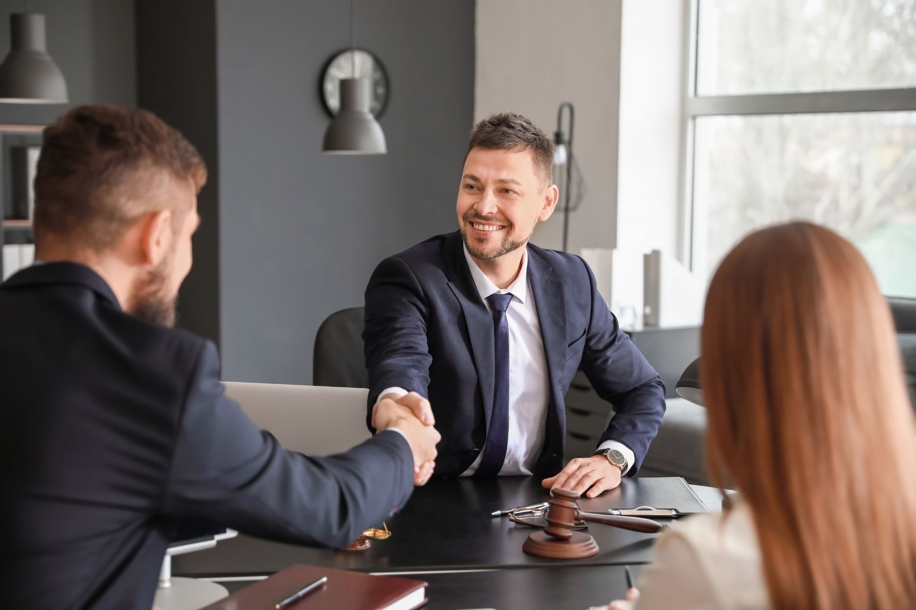 Lemon law attorney shaking hands with clients across an office desk