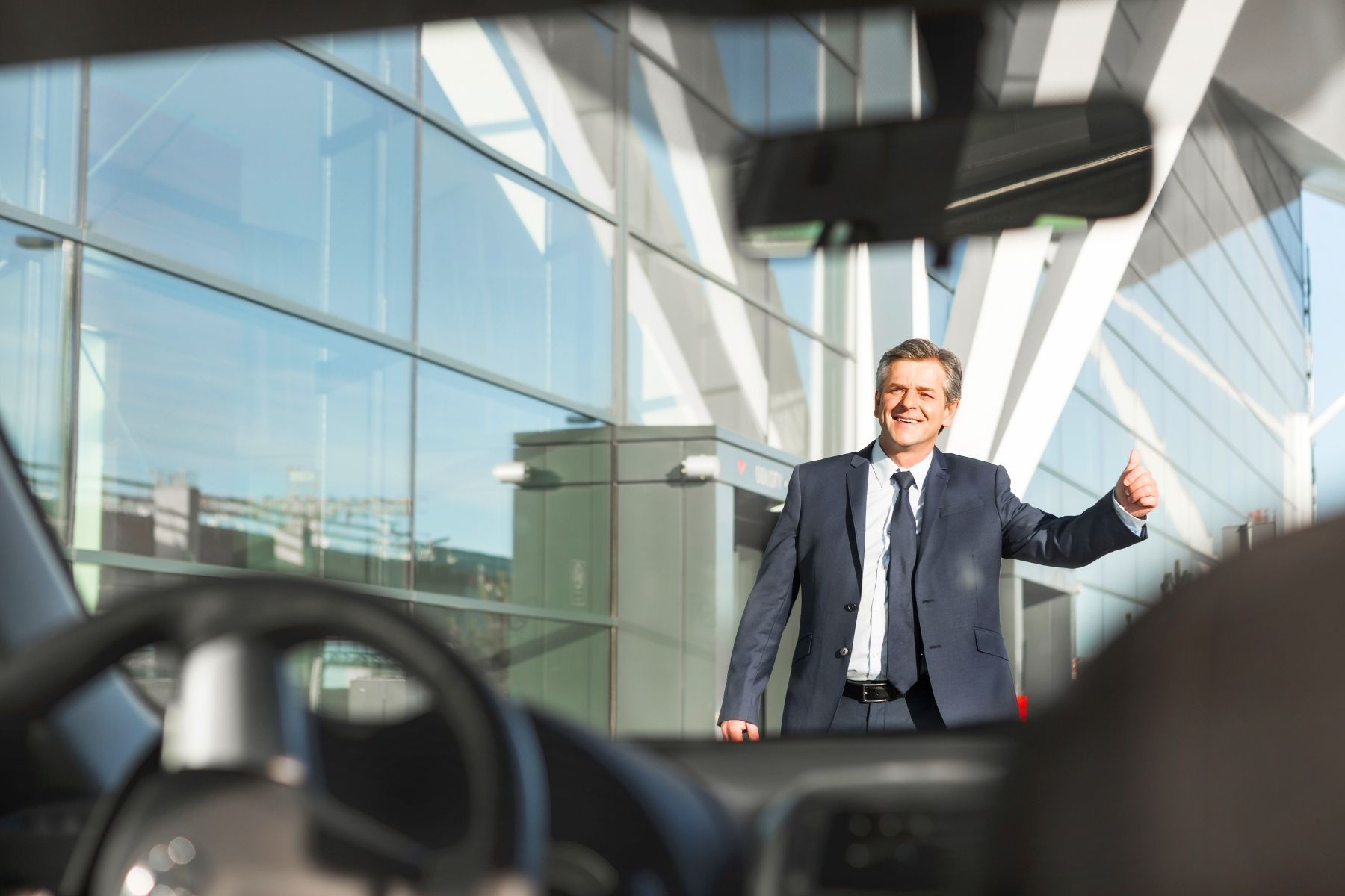 Smiling businessman giving thumbs up outdoors near Volkswagen